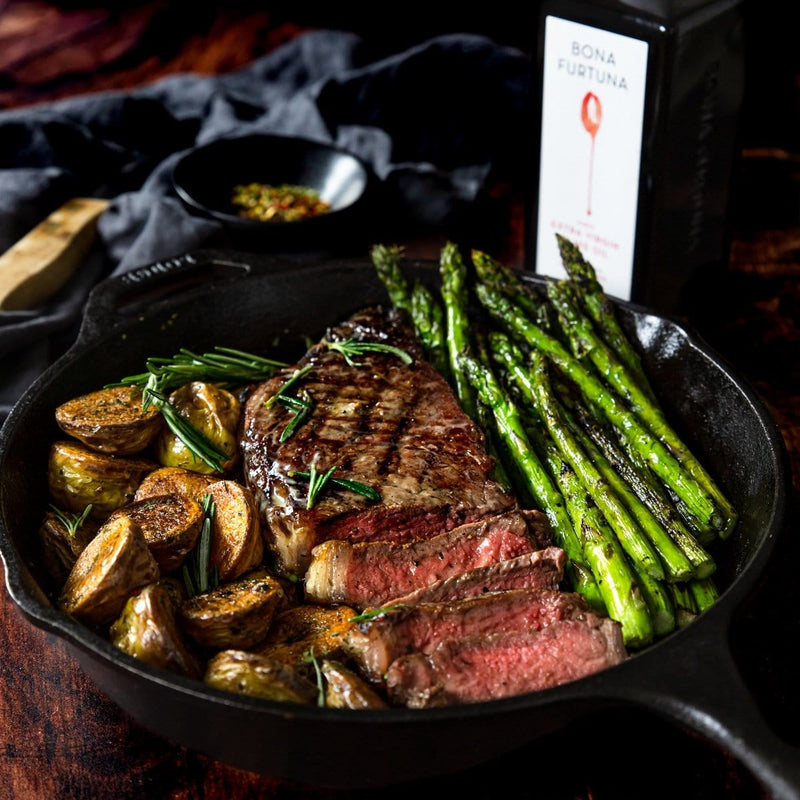 Ribeye steak and sides with olive oil bottle