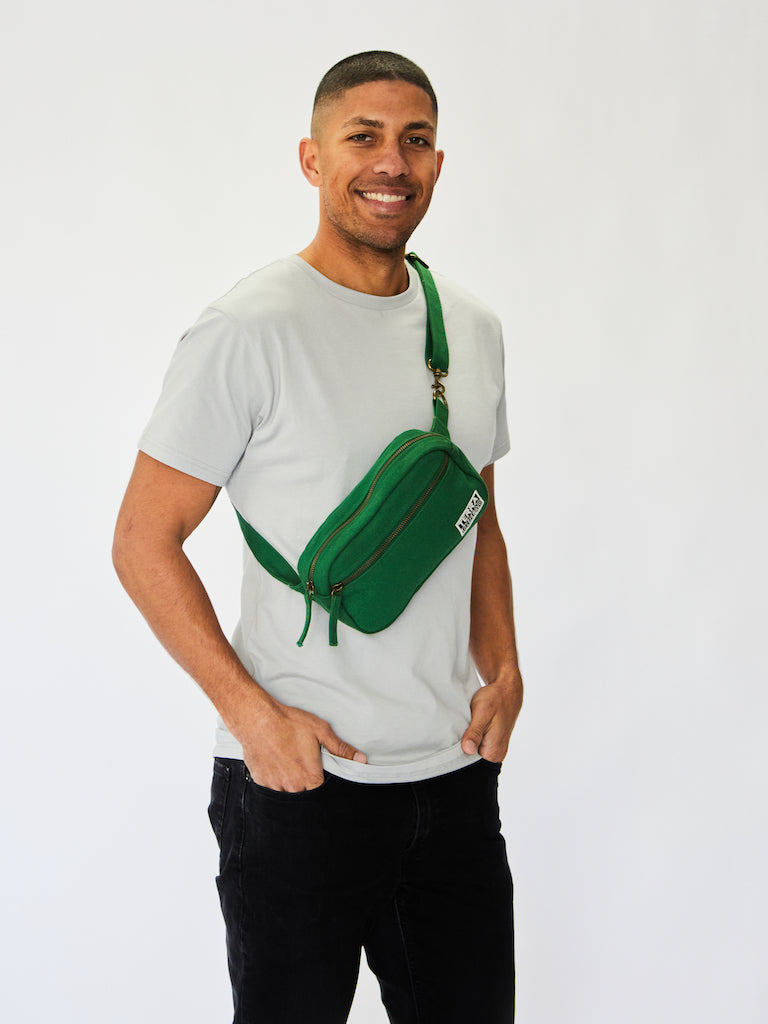 Male model wears sustainable organic cotton fanny pack styled as a shoulder sling bag