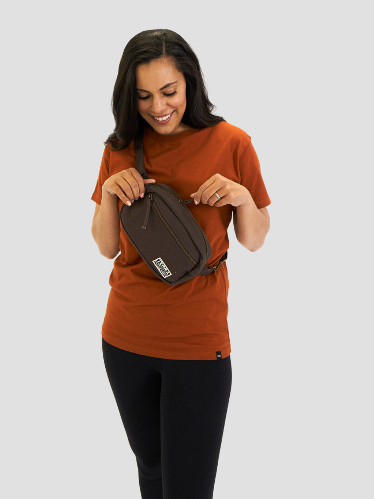 Female model wears sustainable organic cotton fanny pack styled as a shoulder sling bag